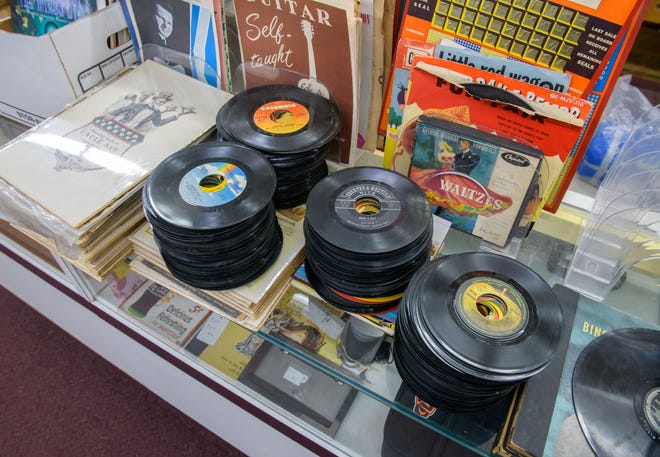 Stacks of 45rpm vinyl records sit atop a display case at A-Z Jewelry & Swap in dowtown Peoria.