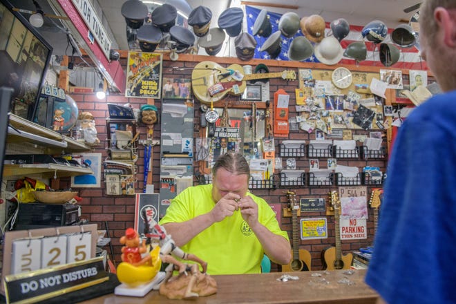 Gary Davis, manager of A-Z Jewelry & Swap Shop, examines some jewelry brought in by a customer of the longstanding pawn shop in downtown Peoria.