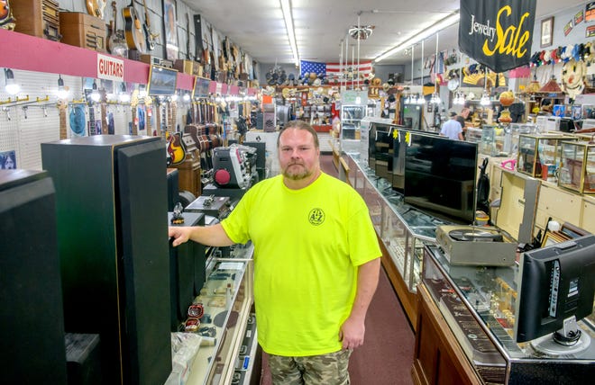 A-Z Jewelry & Swap general manager Gary Davis stands next to rows of speakers, audio equipment and televisions at the longstanding pawn shop in Downtown Peoria.